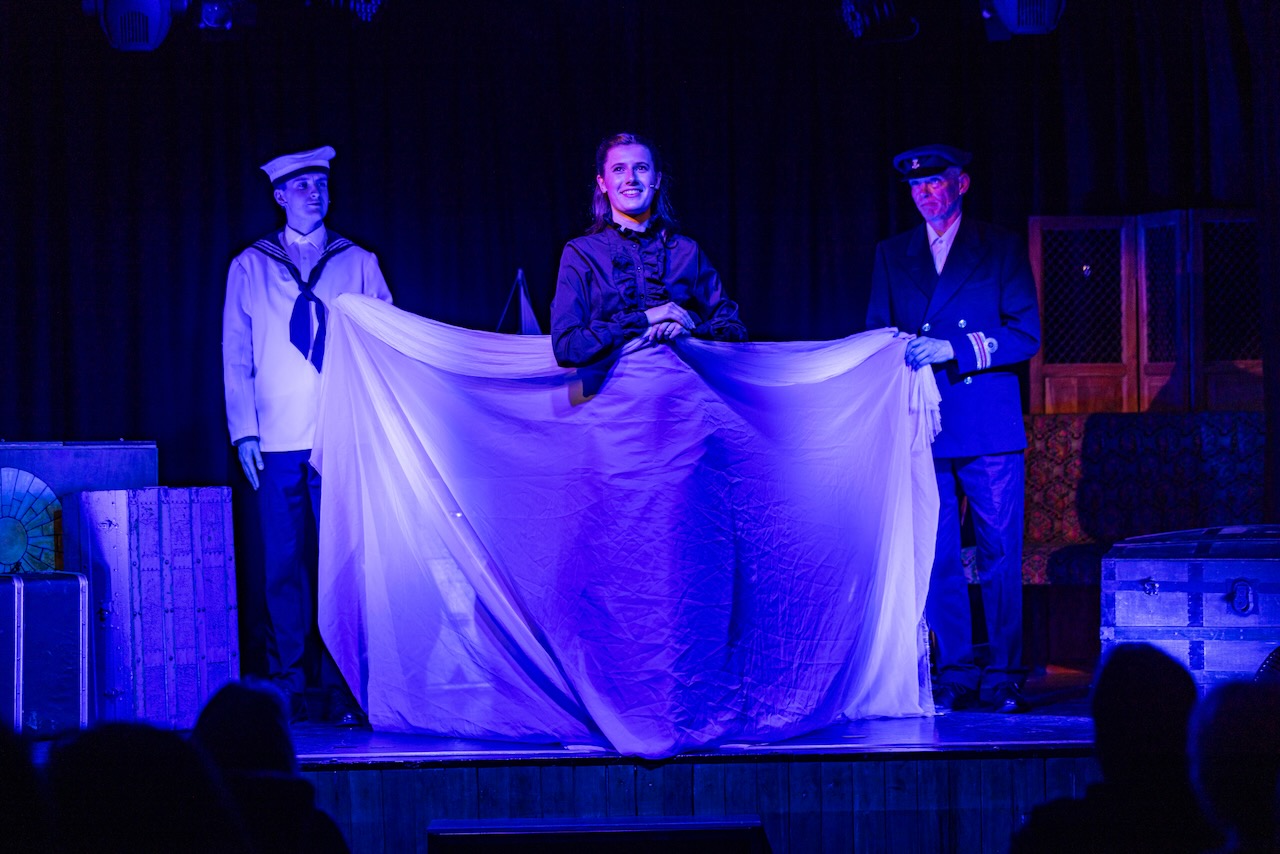 Three actors lit in blue with cloth invoking the sea