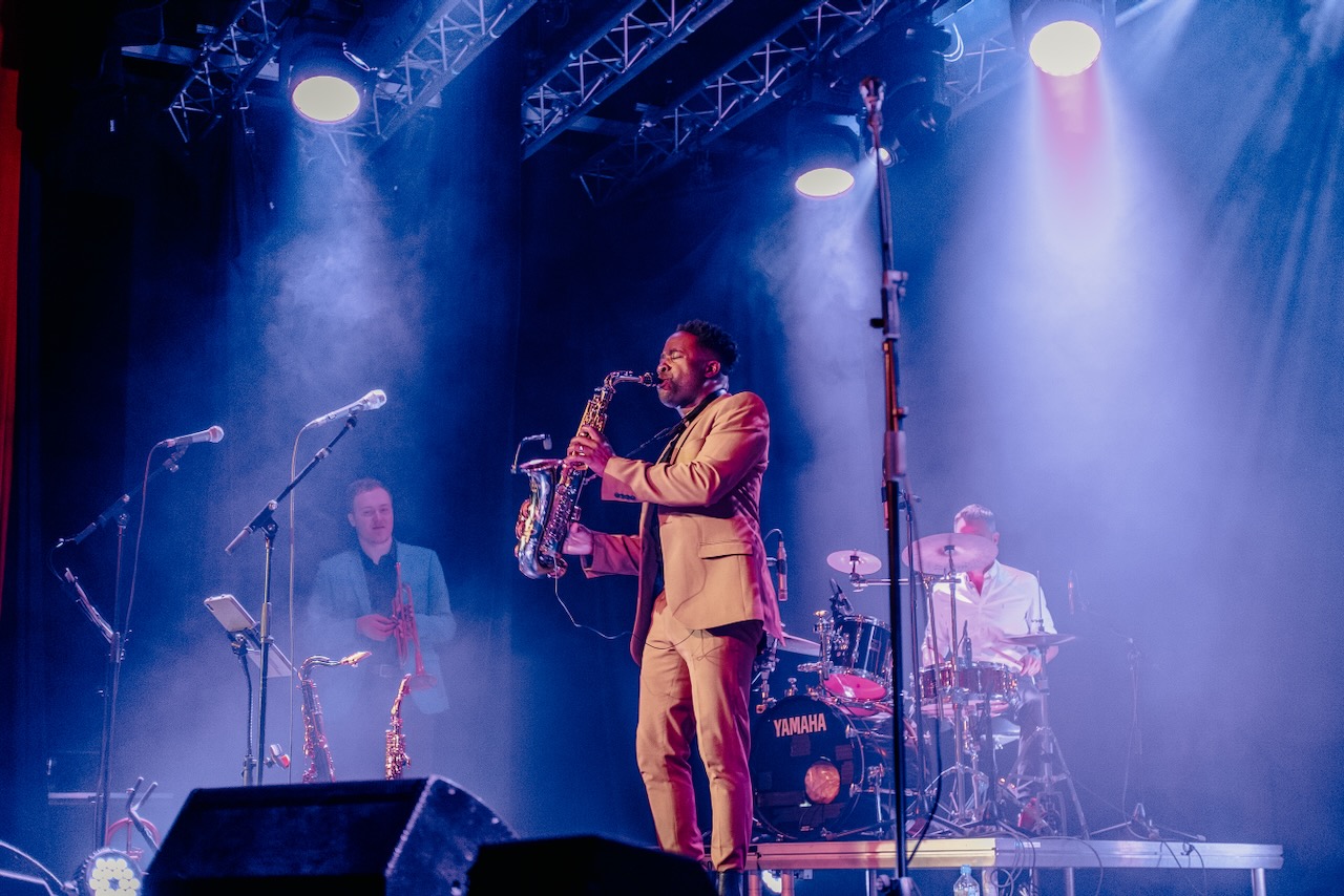 Saxophonist playing a solo on stage under blue spotlights