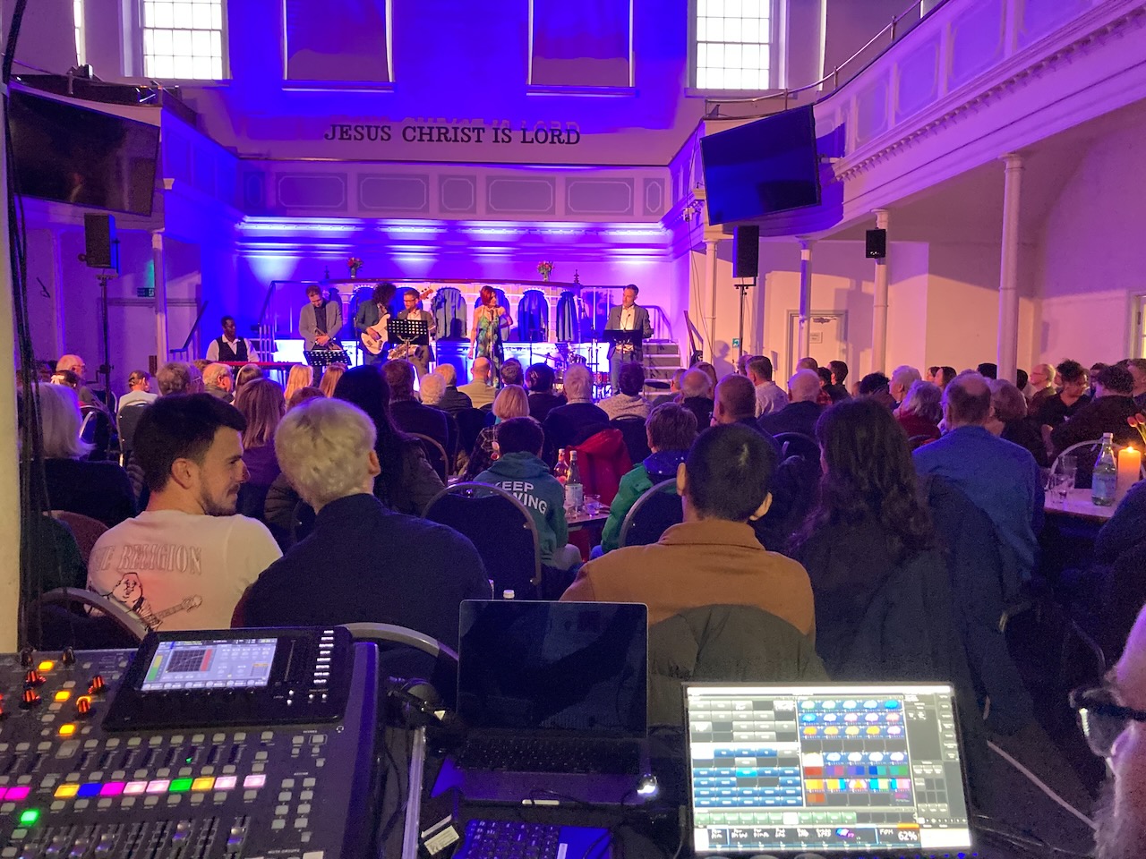 Mixing desk view toward The Roots of Jazz band and audience